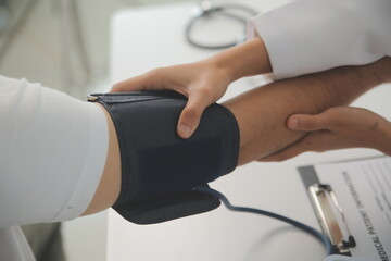 Wall Mural - Male doctor uses a blood pressure monitor to check the body pressure and pulse of the patients who come to the hospital for check-ups, Medical treatment and health care concept.