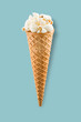Popcorn in ice cream cone on blue background.