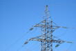 Top section of high-voltage power line metal prop on clear blue sky as background