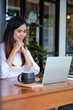 © MIND AND I - Young woman engages in online study or work at cafe.
