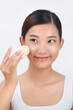 © Marc Tran/Stocksy - Smiling woman using make-up sponge on face
