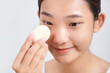 © Marc Tran/Stocksy - Charming girl applying foundation on her face using makeup sponge