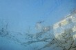 Abstraktes Motiv mit Eismuster vor Häusern und blauem Himmel mit Licht bei Sonne, Frost, Eis und Kälte am Morgen im Winter