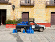 © Shava Cueva/Stocksy - A pickup truck parked on the street full of blue water containers
