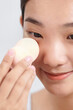 © Marc Tran/Stocksy - Charming girl applying foundation on her face using makeup sponge