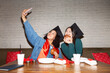 © Danil Nevsky/Stocksy - Happy young girlfriends taking selfie after graduation