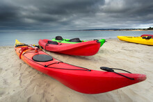 Adventure Amidst The Storm: 4K Ultra HD Image Of Colorful Red Kayak By The Sandy Ocean Beach On A Stormy Day