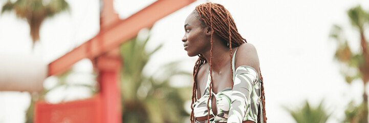 Wall Mural - Gorgeous woman with African braids wearing top stands on the bridge, Panorama