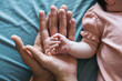 © Pedro Merino/Stocksy - Hands Of A Newborn Baby and her parents