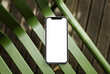 © Artem Podrez/Stocksy - A mock-up of a mobile phone with a white screen on a green chair
