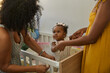 © Edward Córdoba / Andréas Sichel/Stocksy - Baby with mum and granny by crib. The baby looks at her grandma.