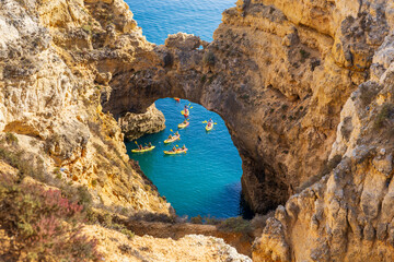 Kayakers in the cathedral arch natural landmark in the Atlantic Ocean at Ponta da Piedade, Algarve coast, Lagos, Portugal.