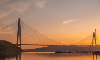 Wall Mural - istanbul yavuz sultan selim bridge taken from the beach towards sunset people dogs with blue sea and sky and evening lighting