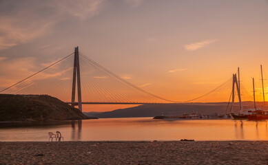 Wall Mural - istanbul yavuz sultan selim bridge taken from the beach towards sunset people dogs with blue sea and sky and evening lighting