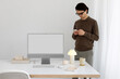 © Artem Podrez/Stocksy - A young man in a office near a computer. White computer screen, mockup