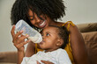 © Edward Córdoba / Andréas Sichel/Stocksy - A woman feeds her daughter with a baby bottle full of formula milk.