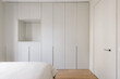 © Nibuya Qubik/Stocksy - Minimalist bedroom with a wall full of closets