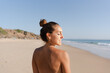 © Raul Navarro/Stocksy - back portrait of a smiling woman at the beach