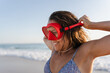 © Raul Navarro/Stocksy - portrait of a woman on the beach with red diving goggles.