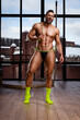 © Serge Lee - Handsome naked man in thong posing in loft studio. Male fitness model with six pack abs wearing green socks and holding green jump rope. Muscular guy in seductive underwear with sports equipment