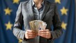 Businesswoman in suit holding euro bills with blurred eu flag for finance concept.