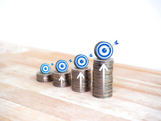 Wall Mural - Business goal and success, sales revenue, savings target, investment and financial concepts. Increasing arrow on Blue target icon on coin stacks, growth graph step on wooden table on white background.