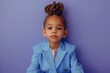 Surrounded by a solid periwinkle canvas, a cute and extremely beautiful kid model in business attire captures attention with a perfect hairstyle and a confident demeanor.