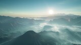Fototapeta  - An aerial perspective of Bromo at sunrise, capturing the expansive view of the mountain range and the surrounding caldera filled with morning mist, with the sun gracefully rising in the background. 8k