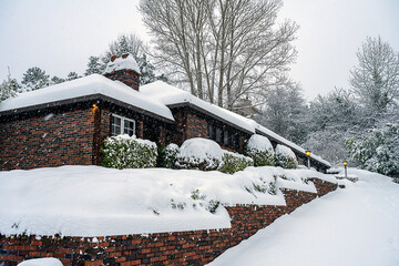 2023-12-31 A BRICK BUILDING COVERED WITH SNOW AND A BLOCKED DRIVEWAY WITH SNOW FALLING ON MERCER ISLAND WASHINGTON