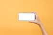 © Gatot - Hand holding blank smartphone in landscape mode for mockup isolated on yellow background