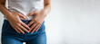 Woman in casual attire holds lower abdomen, showing signs of discomfort, possibly due to premenstrual syndrome. white background, copy space