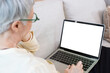 © eakgrungenerd - Senior woman grey hair wear glasses using laptop with white screen computer. relaxing elderly female having video chat white display. technology and old age concept.