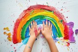 Fototapeta  - the hands of a small child drawing rainbow on the white wall with bright color paint