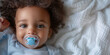 Cute little afroamerican baby with pacifier in cozy bedding. Banner with copy  space. Shallow depth of field.