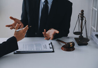 Justice and Law concept. Legal counsel presents to the client a signed contract with gavel and legal law or legal having team meeting at law firm in background