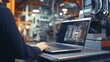 A man focused on his work using a laptop in a factory setting. Suitable for industrial, technology concepts