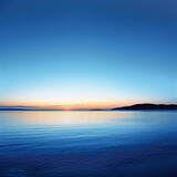 Fototapeta Niebo - A beautiful blue ocean with a sunset in the background