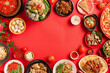Chinese New Year festival table set over a red background featuring traditional Lunar New Year food. Flat lay, top view.