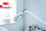 Fototapeta Pomosty - Cosmetic lamp magnifier close up in the office of a dermatologist in a cosmetology clinic