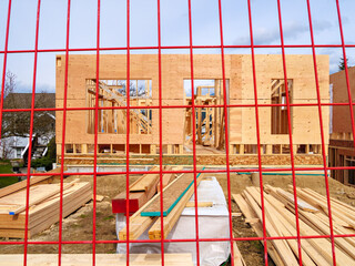 Wall Mural - Wooden frame and walls of new house behind the red fence grid