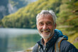 © Apinya - Man in his 50s  60s who exudes happiness and a sense of feeling truly alive in a beautiful natural park near a lake, genuine smile on his face