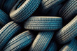 Stacked used car tires against blue sky background in tire recycling facility