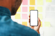 © baranq - Man holding phone with empty mockup screen in office planning business project on whiteboard