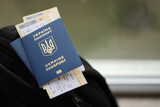 Fototapeta Młodzieżowe - Two ukrainian biometrical passports with air flight tickets on black touristic backpack close up