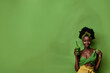 © Noble Nature - jeune femme noire de peau, coiffure afro qui tient à la main une boisson verte, type green smoothie. Le mannequin est habillée en vert et jaune, Fond vert avec espace négatif copyspace