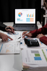 Fototapete - Two people are looking at a laptop with a screen showing graphs and charts