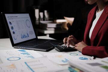 Fototapete - A woman is working on a laptop with a calculator on the table