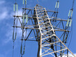 Top section of high-voltage power line metal prop over blue sky angled view