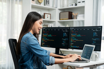 Smiling young Asian in IT developer creating with typing online information on laptop with coding program data of application, wearing jeans shirt. surrounded by safety analysis two screen. Stratagem.