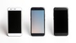 Three modern cell phones lined up on a surface. Suitable for technology concepts